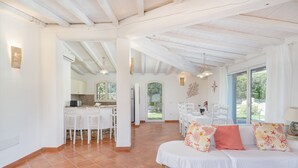 A spacious room with a stone accent wall, white furniture, and a view of the outdoors.