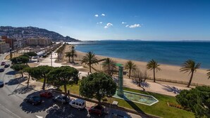 A coastal cityscape with a beach, palm trees, and a clear sky. - Agi Panama 4C Apartamento for rent in Roses Girona. (Roses)