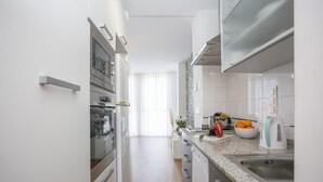 Une cuisine moderne avec des meubles blancs, des appareils en acier inoxydable et un plan de travail en granit.