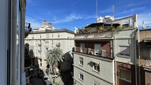 Un immeuble à plusieurs étages doté de balcons, d’un palmier et surplombant un ciel bleu azur.