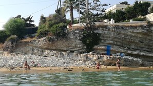 A beach with people sitting and standing on the sand, a rocky cliff in the background, and a body of water in the foreground. - villas overlooking the sea (Gallina)