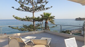 A balcony with a view of the sea, a palm tree, and a chair. - villas overlooking the sea (Gallina)
