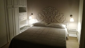 A bedroom with a bed, two bedside tables, a nightstand, and a wardrobe. - villas overlooking the sea (Gallina)