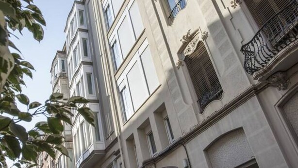 Un edificio de varios pisos con arquitectura clásica, que presenta ventanas simétricas y detalles ornamentales.