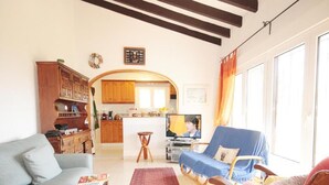 A living room with a sofa, a blue chair, a wooden cabinet, and a television. - Calypso - Javea, Costa Blanca (Javea)