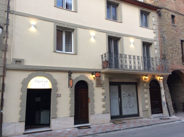 A building with a sign reading "UnipolSai" and a balcony with decorative railings. - L'Arco Charming B&B - Blue Room (Passignano Sul Trasimeno)