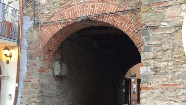Ein Steinhaus mit einem Ziegelbogen, der zu einem schmalen Durchgang führt.