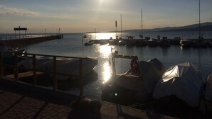 Ein Yachthafen mit vertäuten Booten, eine Mole, die in ruhiges Wasser führt, und ein klarer Himmel.