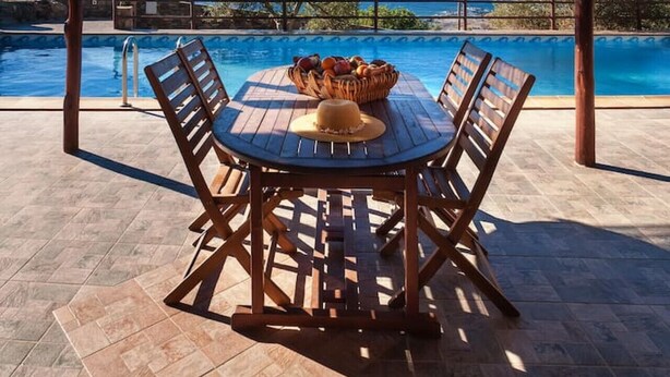 A covered outdoor seating area with a pool and a view of the sea.