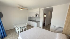 Une chambre d’hôtel de taille réduite comprenant un lit, une kitchenette, un coin repas et une salle de bain.