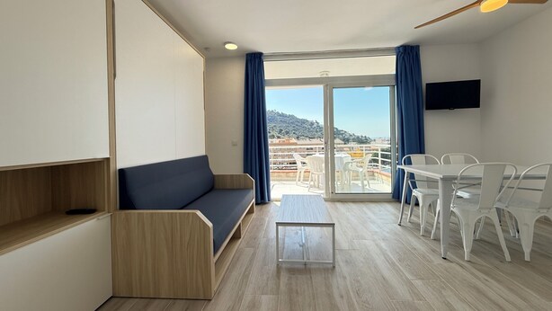 Une chambre moderne avec un canapé, une petite table, une télévision et un balcon offrant une vue agréable.