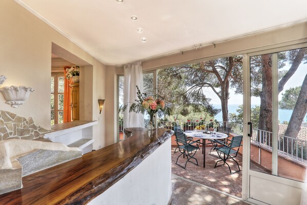 Une cuisine moderne avec un plan de travail en bois, un mur d’accent en pierre et une vue sur un patio agrémenté de meubles d’extérieur et d’arbres.