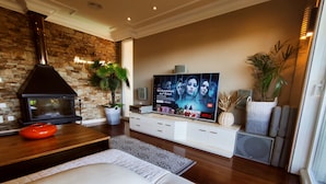 Una sala de estar moderna con pared de piedra, chimenea, televisor de pantalla plana, sofá y una mesa de centro.
