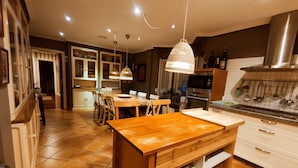 Una cocina moderna con una mesa de comedor de madera, armarios blancos y una campana extractora de acero inoxidable.