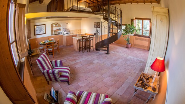 A spacious living area with a high ceiling, a staircase leading to an upper level, a dining area, and a cozy seating arrangement. - Vocabolo Monache La Maggiore<br>Large loft, loft room, cozy super (Perugia)