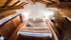 A cozy attic bedroom with a wooden ceiling, a bed with polka dot bedding, and a wooden desk. - Vocabolo Monache La Maggiore<br>Large loft, loft room, cozy super (Perugia)