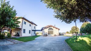 A paved driveway leading to a two-story house with a stone garage and a covered porch. - Vocabolo Monache La Maggiore<br>Large loft, loft room, cozy super (Perugia)