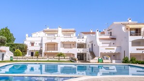 A poolside view of a resort with white buildings, balconies, and a clear blue sky. - JARDINS I 22 Roses (Rosas / Roses)