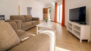 Un salon moderne avec un canapé, une table basse, un téléviseur et une vue sur l’extérieur.