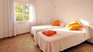 Une chambre avec deux lits, une fenêtre avec des rideaux et un parquet disposé en point de Hongrie.