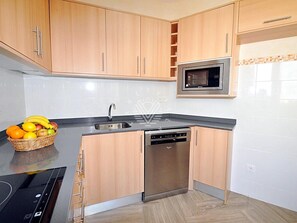 A modern kitchen with wooden cabinets, a built-in microwave, and a dishwasher. - Casa Encinar, villa with garden and private pool (Sa Pobla)