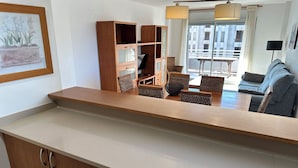 Eine moderne Küche mit Holzausstattung, einer Arbeitsplatte und einem Essbereich mit Korbstühlen und einem Tisch.