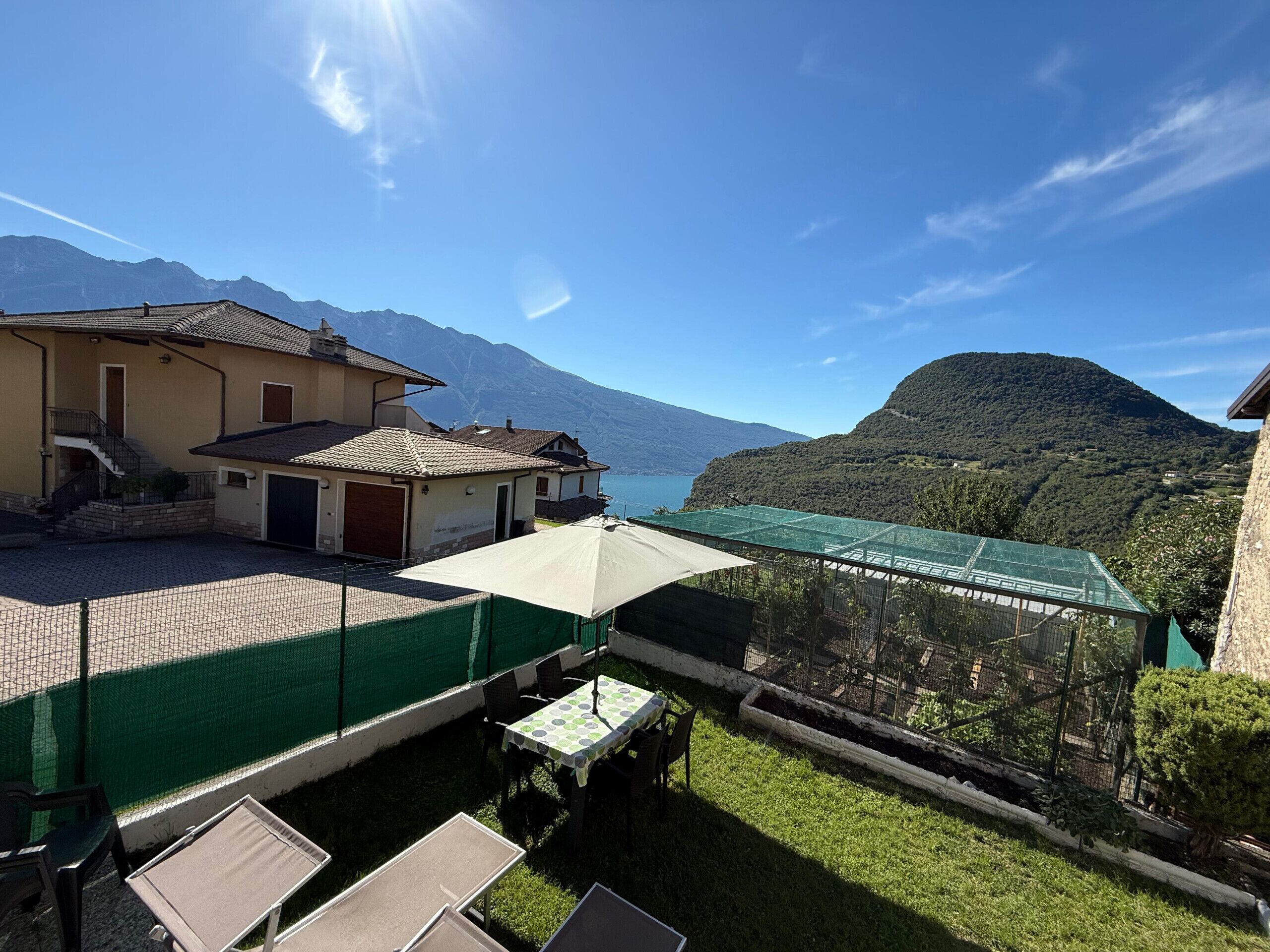 Une terrasse avec des sièges extérieurs, une vue sur les montagnes et un lac.
