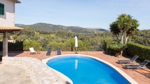 A swimming pool with lounge chairs and a view of a mountainous landscape.
