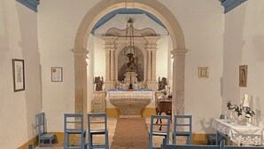 An interior with a central altar, blue chairs, and a carpeted aisle.