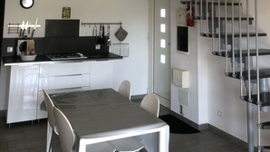 A modern kitchen with a dining area, a staircase, and a small window.