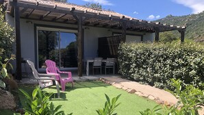 A covered patio with outdoor seating, a grassy area, and a view of a mountain.