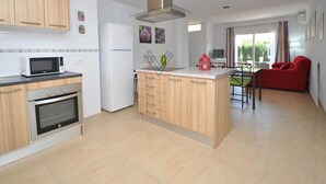 Una cocina moderna con gabinetes de madera, una campana extractora de acero inoxidable y un microondas empotrado.