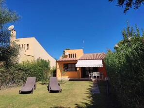 A two-story building with a tiled roof, a satellite dish, and a small patio area with a table and chairs. - New Valmar Three-room apartment 39 (Costa Rei)