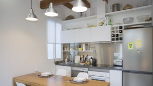Une cuisine moderne avec des armoires blanches, des appareils en acier inoxydable et des luminaires suspendus.