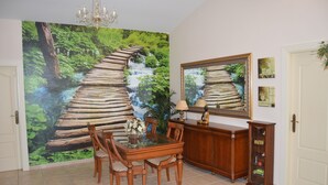 Ein Essbereich mit Holztisch und -stühlen, einer Kandelaber und einem großen Wandbild eines Walwasserfalls.