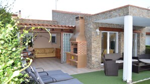 Ein Patio mit Backsteinkamin, Gartenmöbeln und einer überdachten Sitzgruppe.