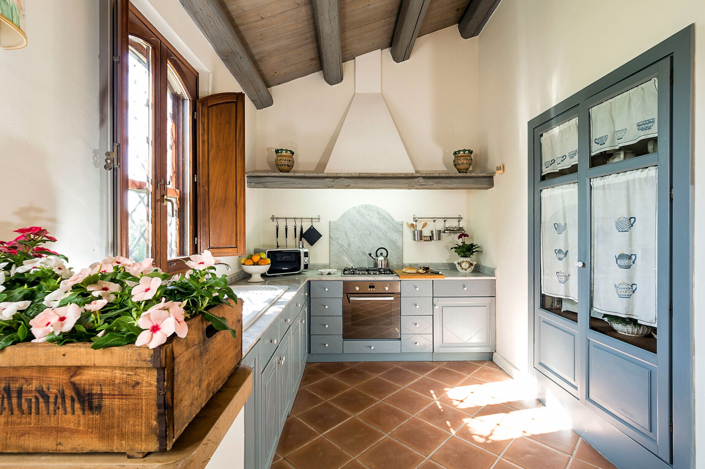 Una cucina con mobili in legno, pavimento piastrellato e piano di lavoro in legno.
