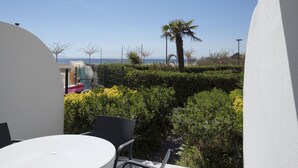A balcony with a table and chairs, a view of the sea, and some greenery. - Nice apartment in front of the sea in Roses Inmosantos Oasis E2 (Rosas / Roses)