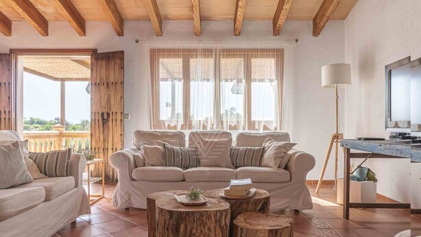 Ein großzügiges Wohnzimmer mit einer breiten beigen Couch, einem Holztisch und einem Fernsehschrank.