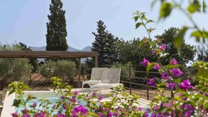 Ein Poolbereich mit zwei weißen Liegestühlen und einer Pergola.