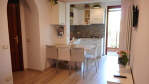 Una cocina moderna con armarios blancos, una zona de comedor con sillas y una pequeña mesa.