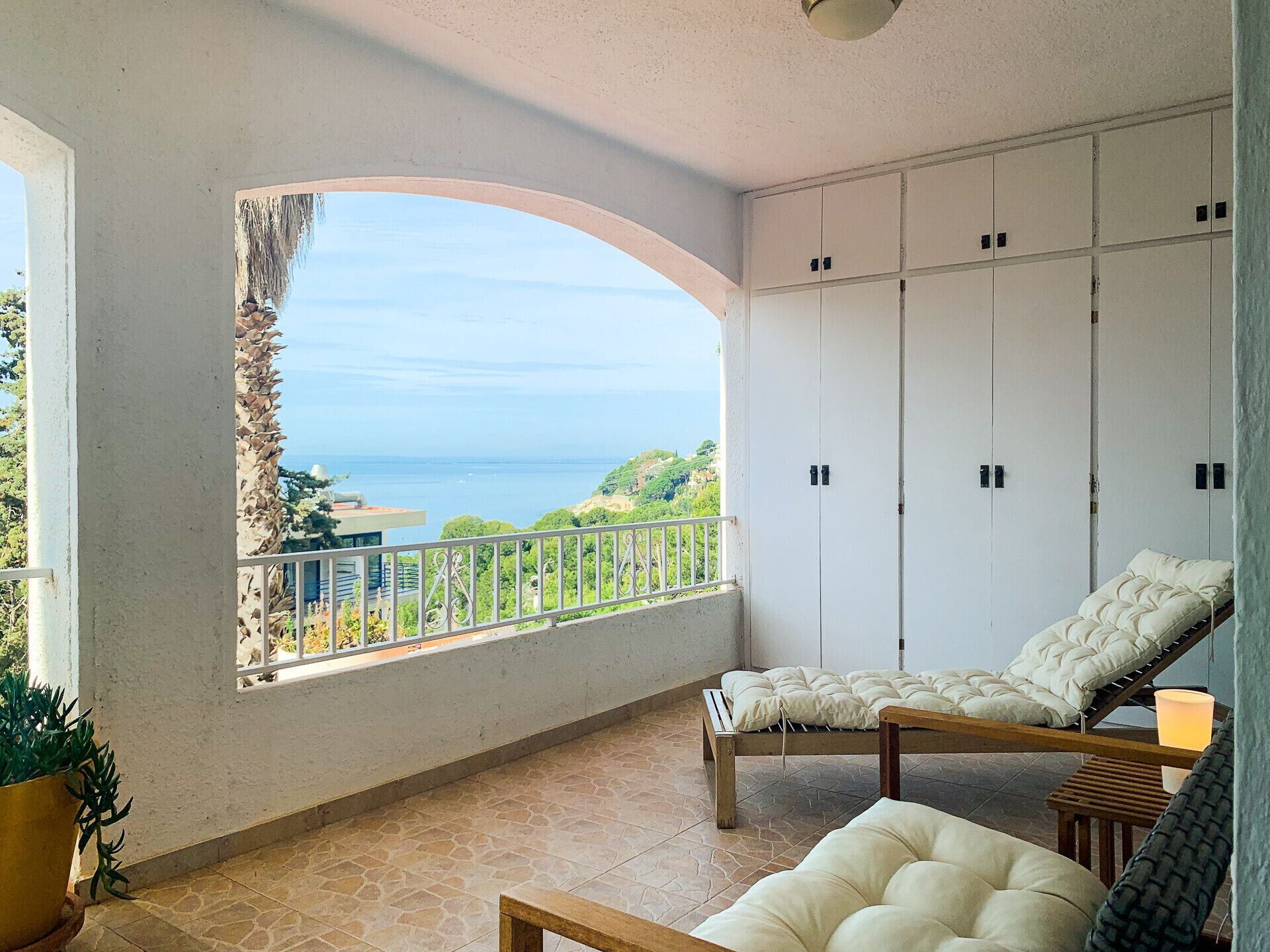 Un balcon avec vue sur la mer, un lit et une armoire.