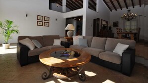 A spacious living area with a large sectional sofa, a round wooden coffee table, and a potted plant. - Son Horlandis, Country house in Petra, Mallorca (Petra)