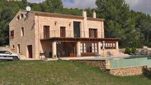 A stone building with a balcony, a swimming pool, and a car parked in front. - Son Horlandis, Country house in Petra, Mallorca (Petra)
