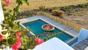 A hot tub with a wooden deck and a watermelon float, surrounded by a fence and dry grass. - PAROS HOUSE - Ground Floor of a Villa for 6 persons Private Pool and Sea View (PAROS)