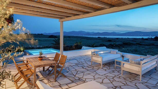 A covered outdoor seating area with a pool, stone flooring, and a view of the landscape. - PAROS HOUSE - Ground Floor of a Villa for 6 persons Private Pool and Sea View (PAROS)