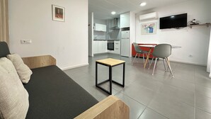 A modern living room with a sofa, a small table, and a dining area with chairs. - Agi Arago 151 Apartamento for rent in Roses Girona. (Rosas / Roses)