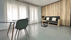 A modern living room with a sofa, a coffee table, and a dining table with chairs. - Agi Arago 151 Apartamento for rent in Roses Girona. (Rosas / Roses)
