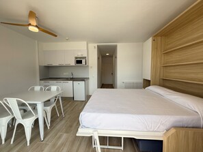 A compact room with a bed, a dining table with chairs, a kitchenette, and a ceiling fan. - Agi Rescator 217 Apartamento for rent in Roses Girona. (Rosas / Roses)