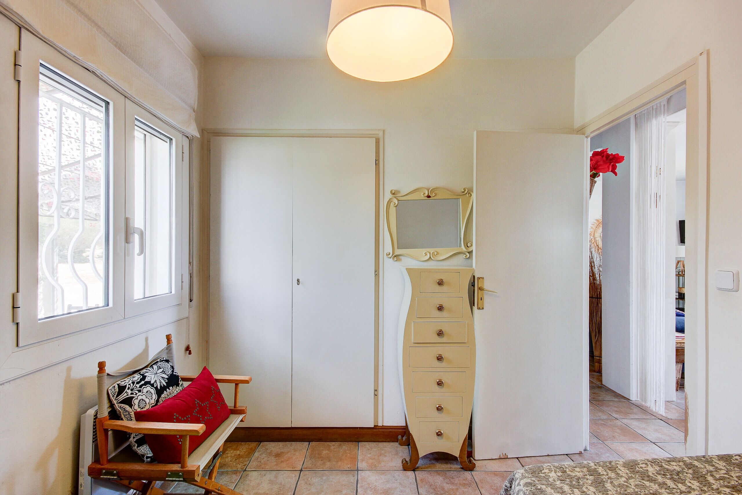 A room with a bed, a dresser, a mirror, and a window.